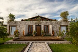 Charming stone house with lush plants and blue sky, ideal for architecture and nature photography.